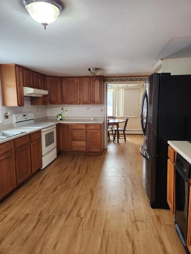 kitchen with tasteful backsplash, black fridge, white range with electric stovetop, and light hardwood / wood-style flooring