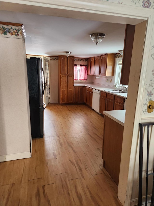 kitchen with fridge, sink, white dishwasher, and light hardwood / wood-style floors