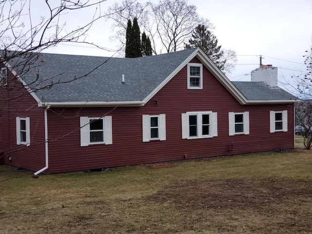 view of home's exterior featuring a yard, a shingled roof, and a chimney