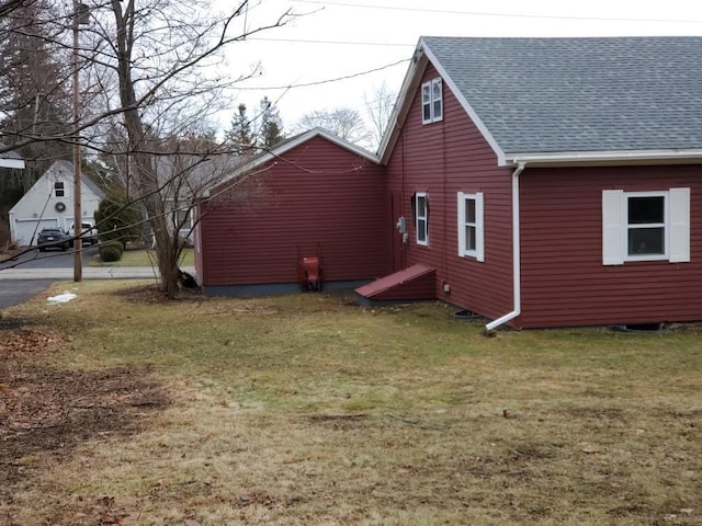 view of property exterior featuring roof with shingles and a yard