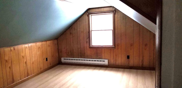 bonus room with light wood-type flooring, a baseboard radiator, wooden walls, and vaulted ceiling