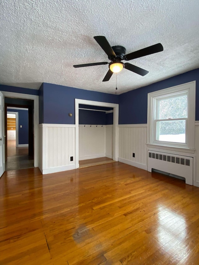 interior space featuring radiator, a closet, wood finished floors, and wainscoting