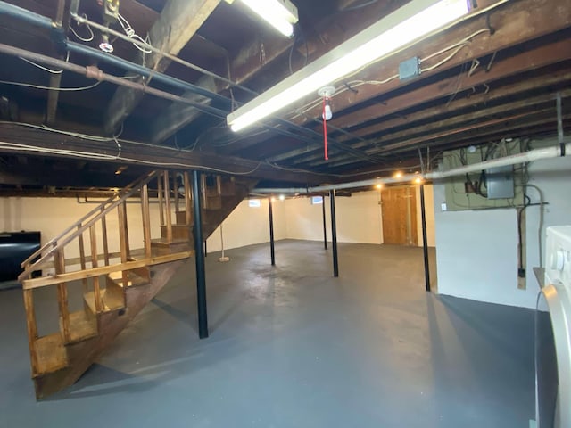 unfinished basement with heating fuel, stairs, and washer / clothes dryer