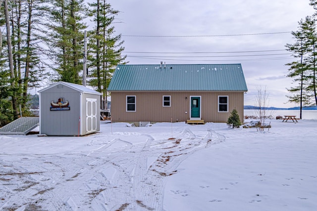 snow covered rear of property with a storage shed