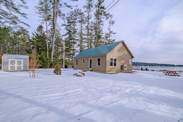 snow covered property featuring a water view and a shed