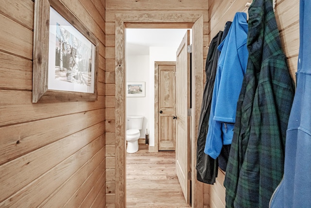 hall with light hardwood / wood-style flooring and wood walls