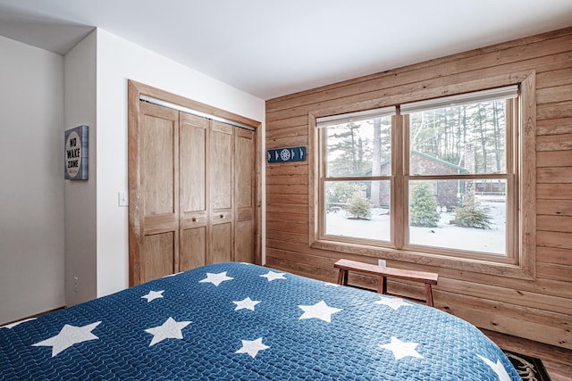 bedroom with a closet and wooden walls