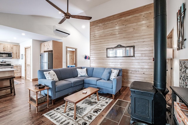 living room featuring an AC wall unit, dark wood-type flooring, wooden walls, a wood stove, and ceiling fan