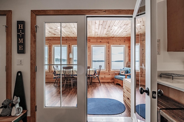 doorway with wooden ceiling, hardwood / wood-style floors, and wooden walls