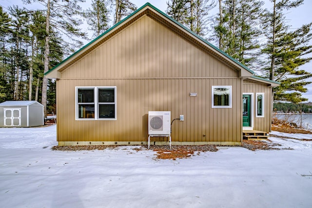 snow covered house with ac unit and a storage shed