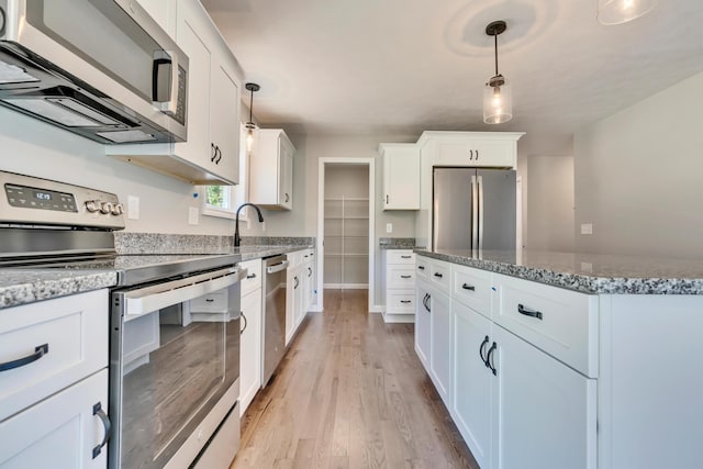 kitchen featuring hanging light fixtures, white cabinets, stainless steel appliances, and stone counters