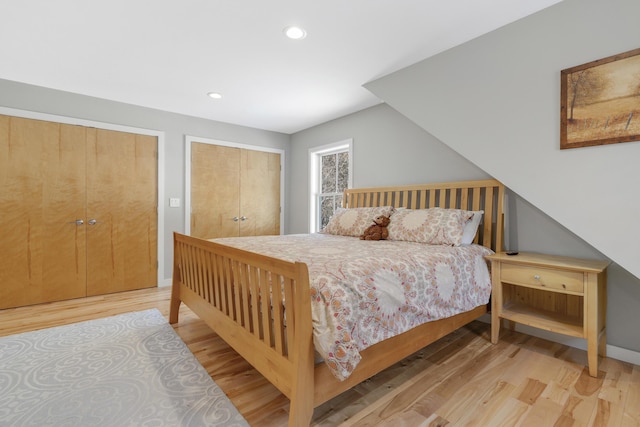 bedroom with two closets and light hardwood / wood-style flooring