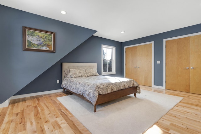 bedroom featuring light hardwood / wood-style flooring and multiple closets