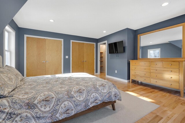 bedroom with multiple closets and light hardwood / wood-style flooring