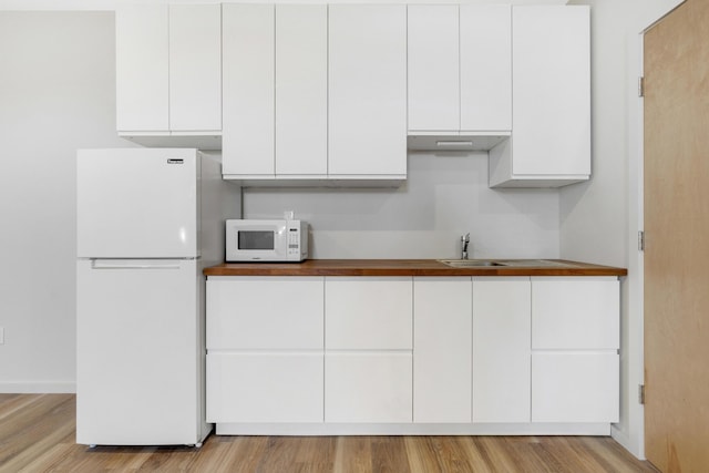 kitchen featuring white appliances, light hardwood / wood-style floors, sink, and white cabinets