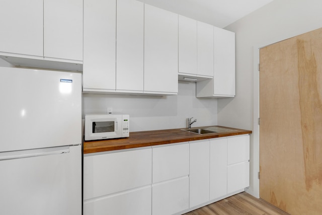 kitchen featuring white cabinetry, white appliances, light hardwood / wood-style floors, and wooden counters