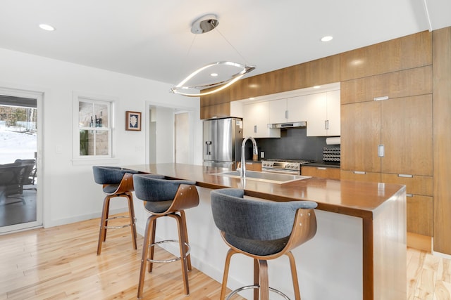 kitchen featuring sink, stainless steel appliances, a kitchen breakfast bar, a spacious island, and white cabinets