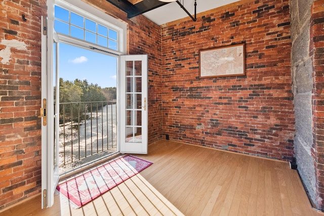 doorway to outside with french doors, brick wall, and light hardwood / wood-style floors