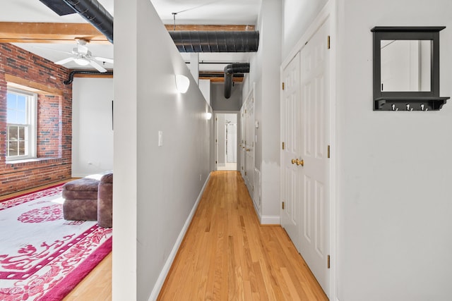 corridor with brick wall, light hardwood / wood-style flooring, and beamed ceiling