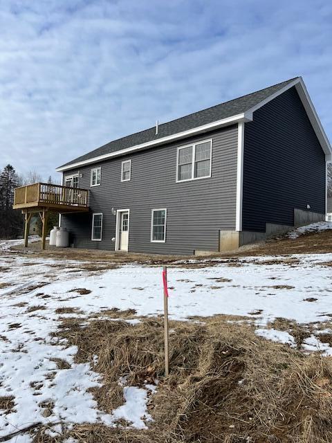 snow covered rear of property with a deck