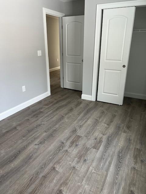 unfurnished bedroom with a closet and dark hardwood / wood-style flooring