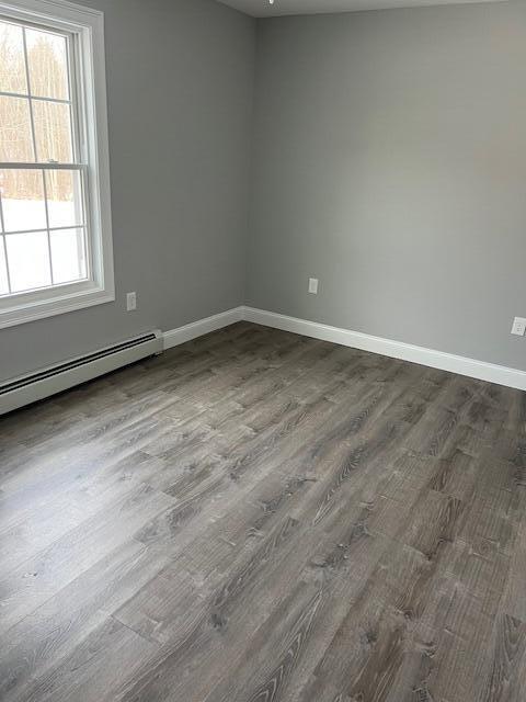 spare room with baseboard heating and hardwood / wood-style floors