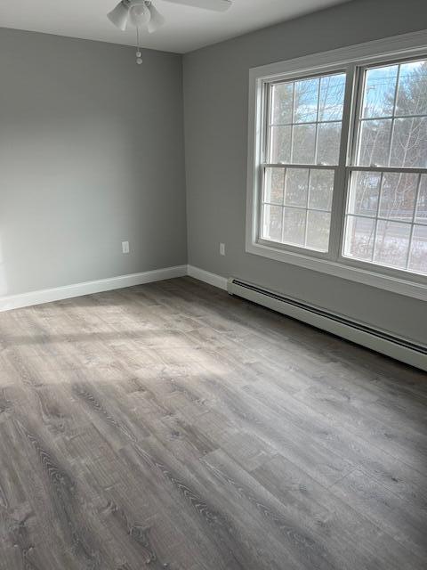 spare room with ceiling fan, wood-type flooring, and a baseboard radiator