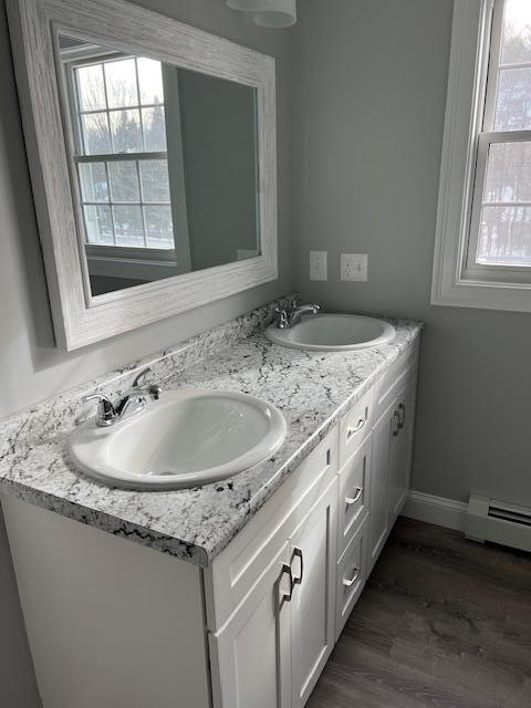 bathroom featuring a healthy amount of sunlight, hardwood / wood-style floors, vanity, and a baseboard radiator