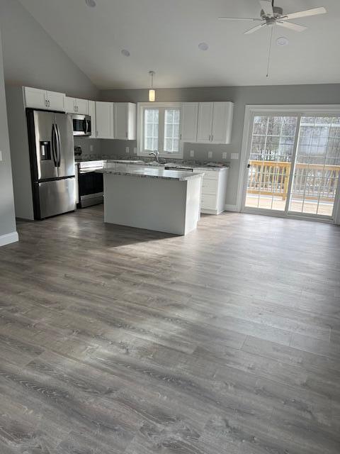 kitchen with hardwood / wood-style flooring, stainless steel appliances, white cabinets, and a center island