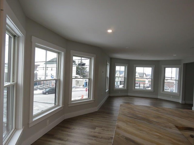 empty room with dark wood-type flooring, a healthy amount of sunlight, and baseboards