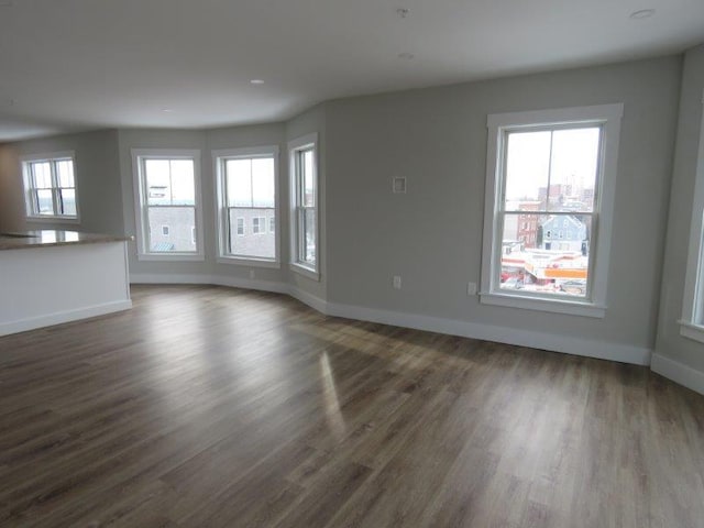 unfurnished living room featuring baseboards and dark wood-style flooring