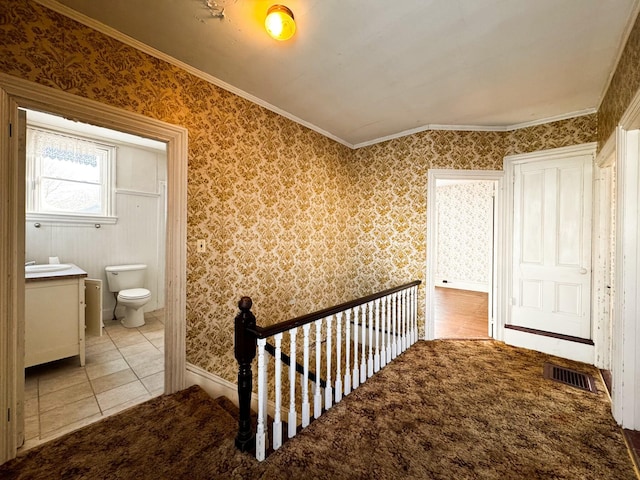 hallway featuring light tile patterned floors, vaulted ceiling, and ornamental molding