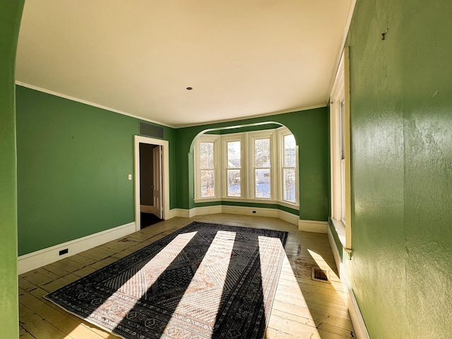 spare room with ornamental molding and light wood-type flooring