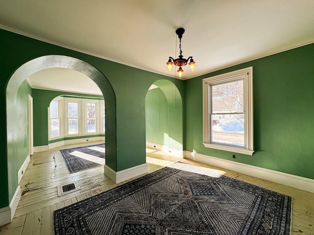 unfurnished room featuring crown molding, light hardwood / wood-style floors, and a chandelier