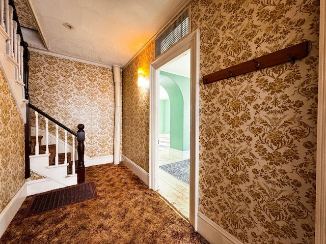 corridor with crown molding and dark colored carpet