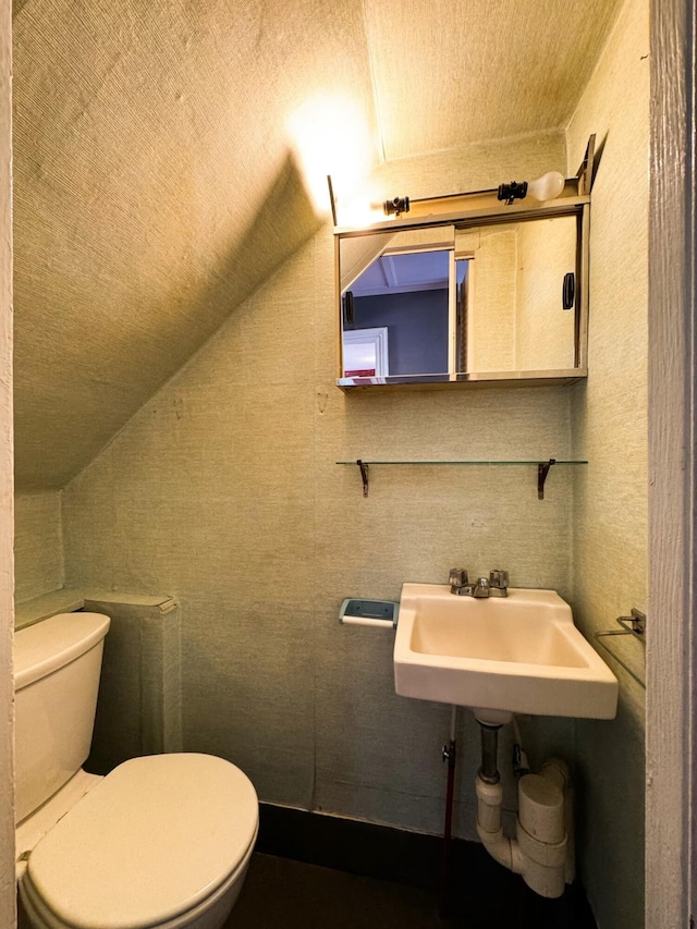 bathroom with sink, toilet, and vaulted ceiling