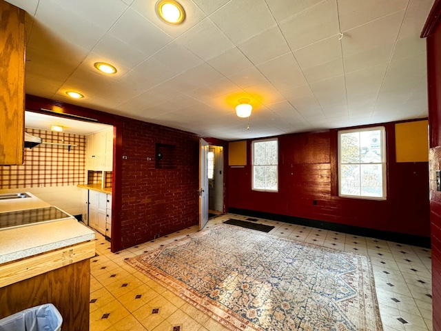 kitchen with black electric cooktop, plenty of natural light, and brick wall