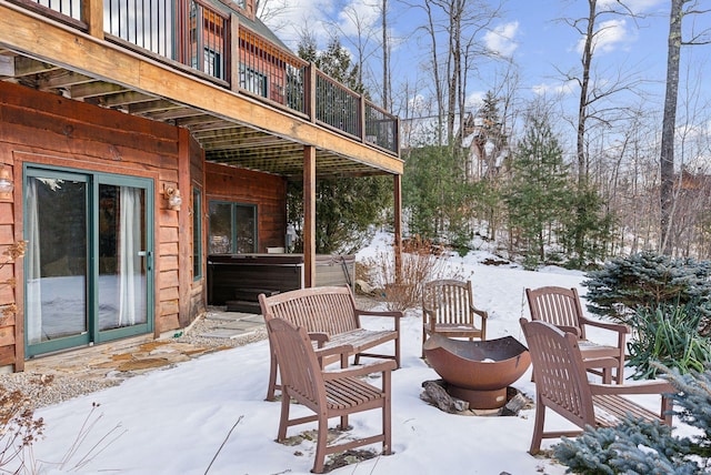 snow covered patio featuring a hot tub and a balcony