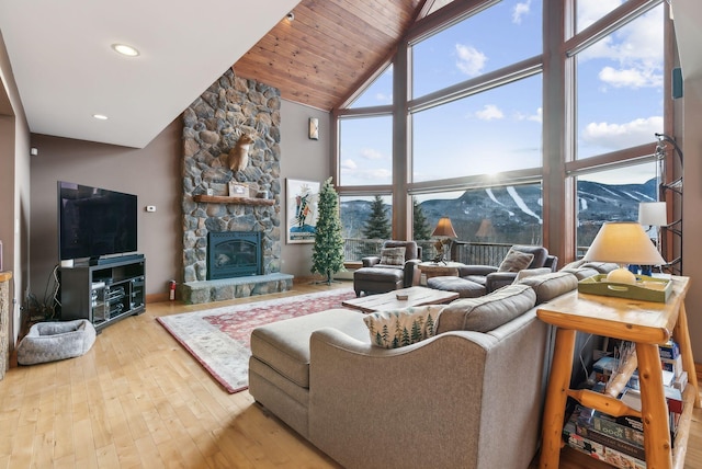 living room featuring a fireplace, wood-type flooring, a mountain view, high vaulted ceiling, and wooden ceiling