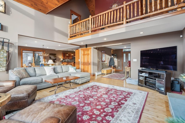 living room with baseboard heating, wood-type flooring, a towering ceiling, and wooden ceiling