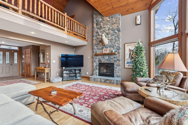 living room featuring high vaulted ceiling, wooden ceiling, hardwood / wood-style floors, and a stone fireplace