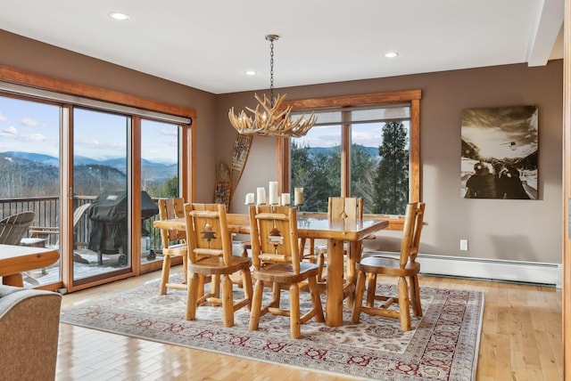 dining room with a baseboard heating unit, an inviting chandelier, a mountain view, and light hardwood / wood-style flooring