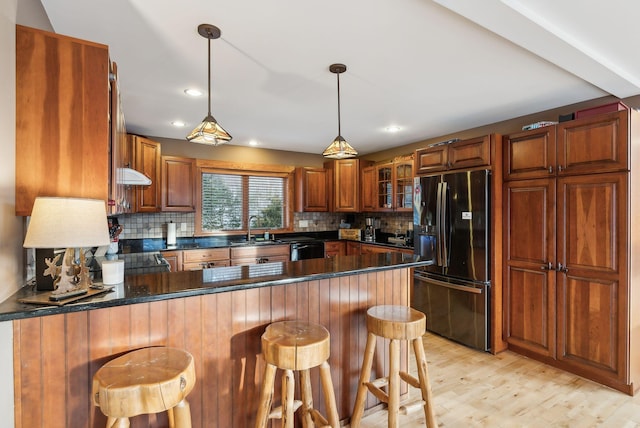 kitchen with black appliances, kitchen peninsula, decorative backsplash, and a breakfast bar area