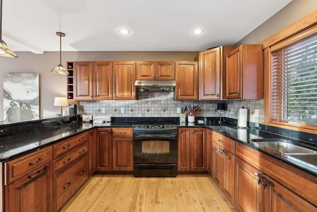 kitchen featuring decorative light fixtures, light hardwood / wood-style floors, black / electric stove, and dark stone counters