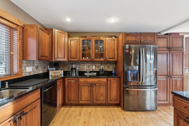 kitchen with stainless steel fridge, tasteful backsplash, dark stone countertops, dishwasher, and light hardwood / wood-style flooring