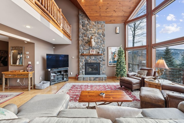 living room featuring high vaulted ceiling, light wood-type flooring, a fireplace, and wooden ceiling