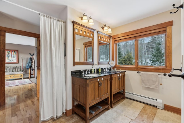 bathroom with hardwood / wood-style flooring, a baseboard radiator, and vanity