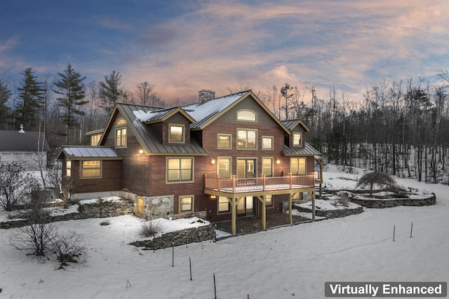 snow covered back of property with a wooden deck