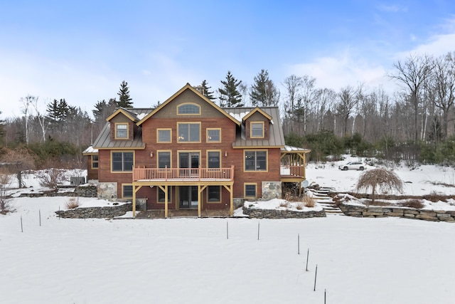 snow covered back of property featuring a wooden deck