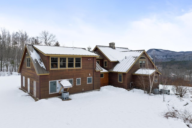 snow covered back of property featuring central AC and a mountain view